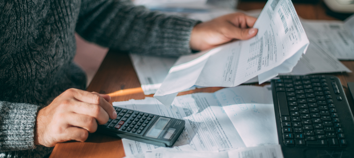 Zbliżenie na dłonie, kalkulator i dokumenty. Grafika dla KSeF - Krajowy System eFaktur