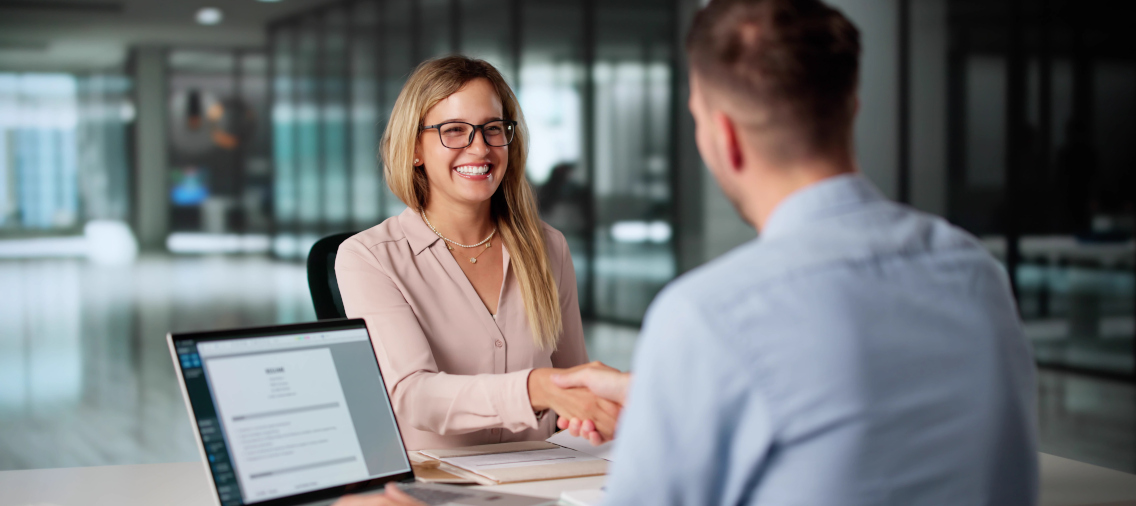 Uśmiechnięta klienta podająca dłoń w geście zawartej umowy.